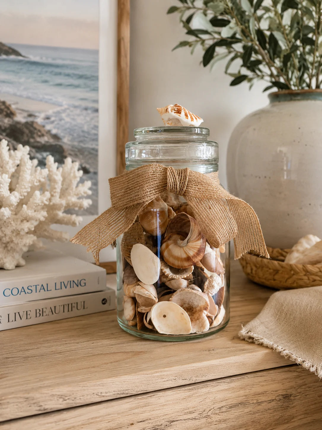 Decorative seashell glass jar with natural bow styled on a timber console in a coastal home